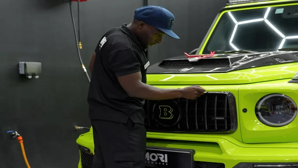 A technician performing expert detailing on a bright green luxury SUV