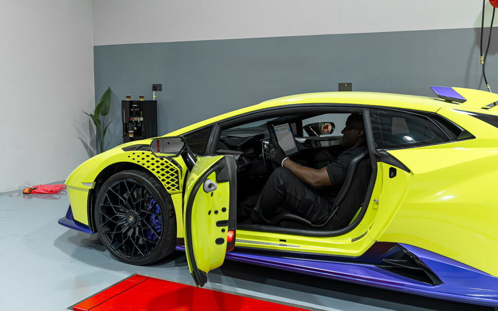 A bright yellow luxury sports car undergoing professional maintenance