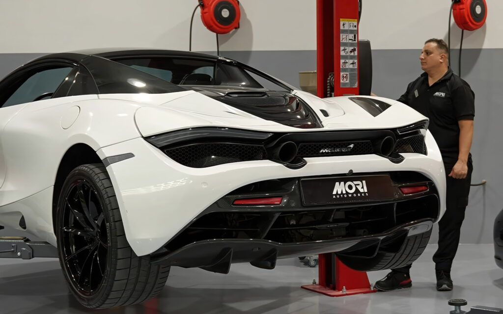 A white McLaren lifted for inspection inside Mori Autoworks luxury car service center.